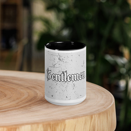 White mug with black interior on a wooden surface, featuring the word 'Gentlemen'.