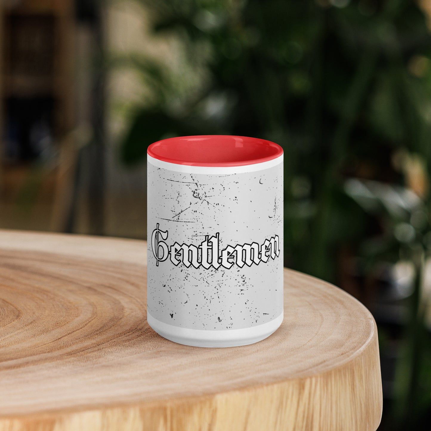Speckled white coffee cup with red inside sitting on a wooden round.