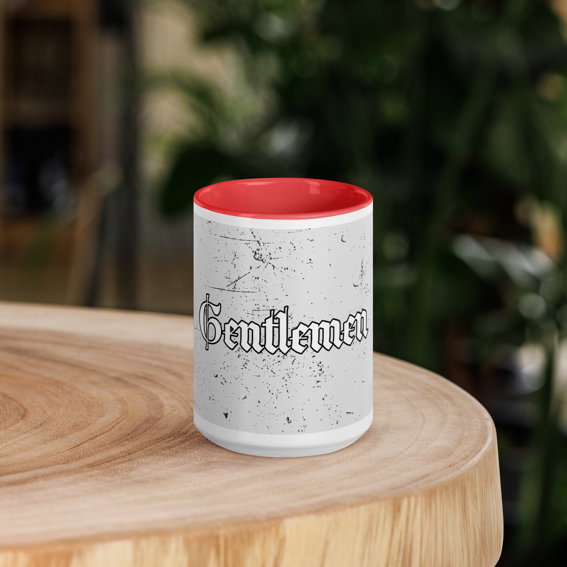 Speckled white coffee cup with red inside sitting on a wooden round.
